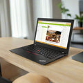 A Lenovo ThinkPad X280 i7 8650U 1.9GHz 16GB 256GB SSD 12.5 W11P laptop is on a wooden desk displaying a workspace page, with blurred plants and light through curtains in the background.