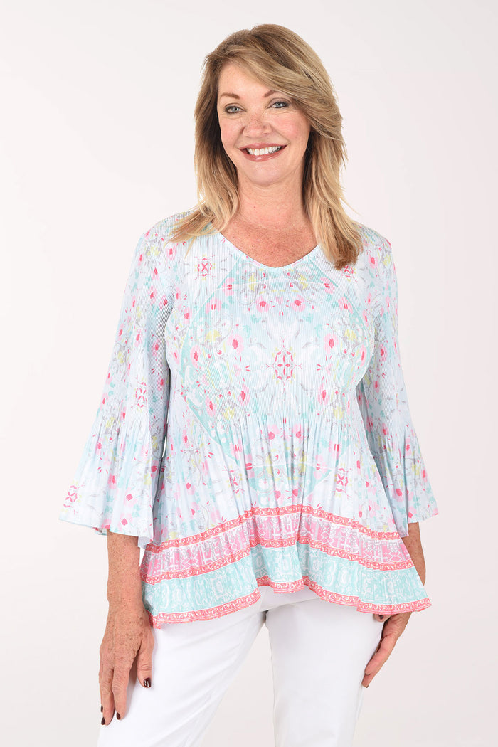 Woman wearing a light blue floral print top with pink trim on a white background